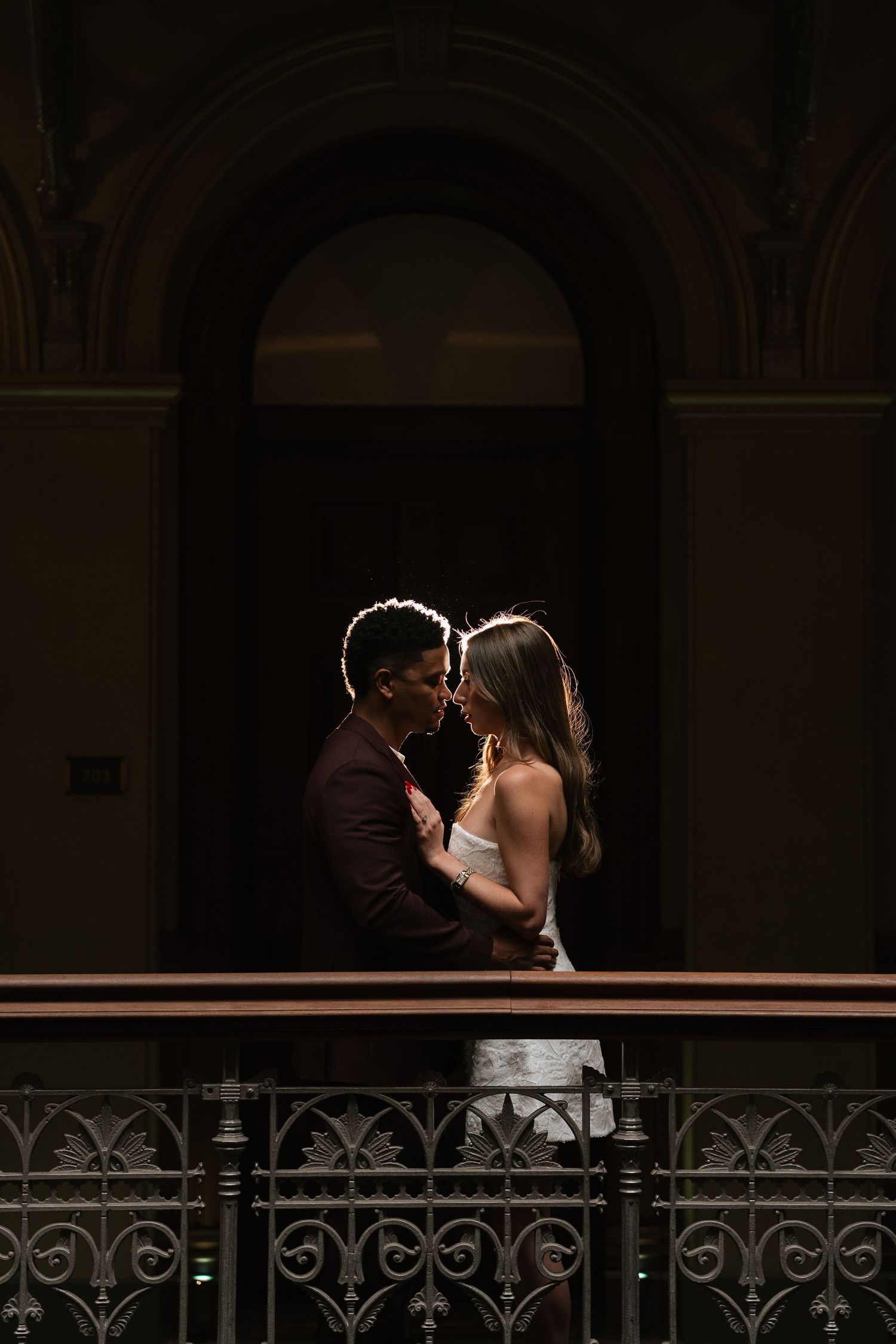 Romantic silhouette photo in dark archway with ornate railing.