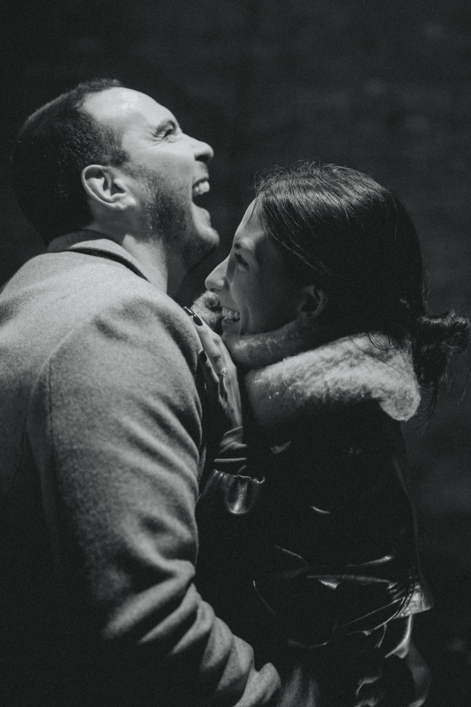 Black and white photo of a laughing couple embracing romantically in a tender, joyful moment.