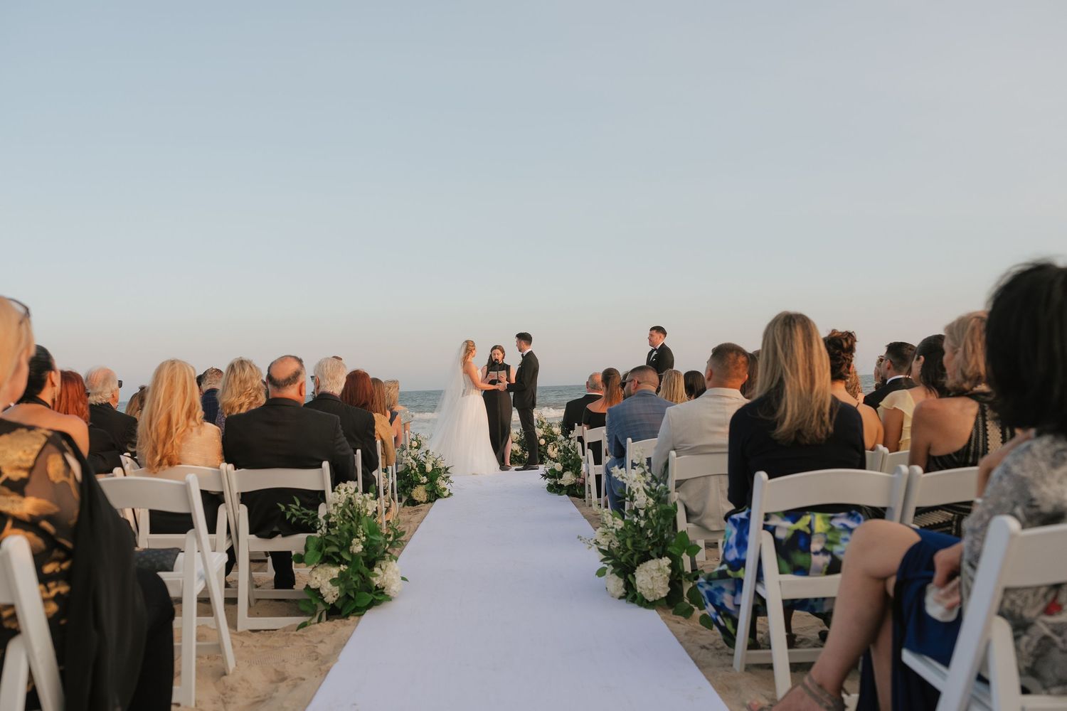 Wedding guests gather outdoors at sunset to celebrate during a scenic reception.