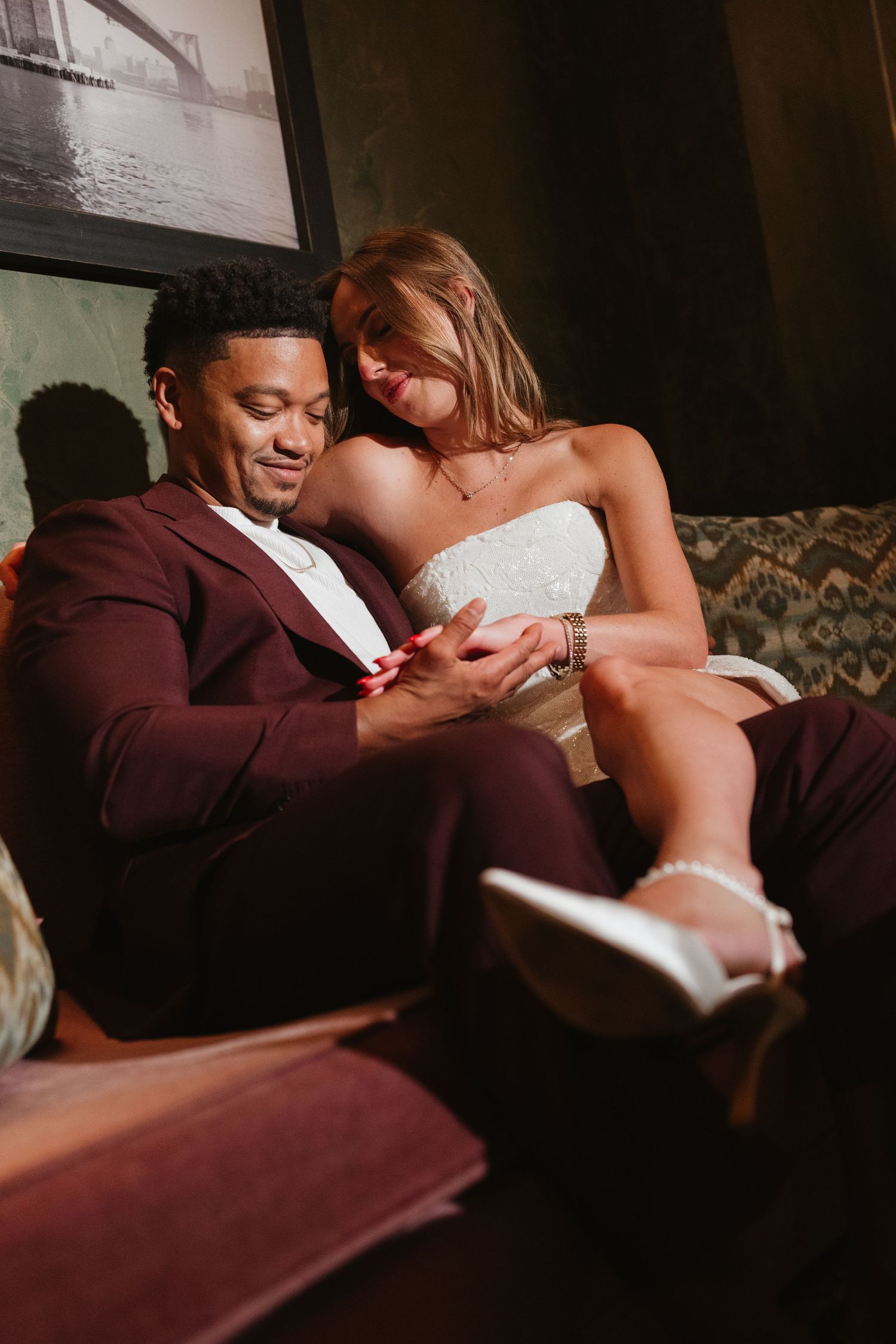 Intimate moment captured on vintage couch in dramatic lighting.