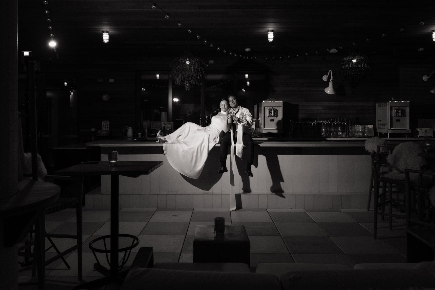 Black and white photo of a groom lifting his bride at a wedding reception venue.