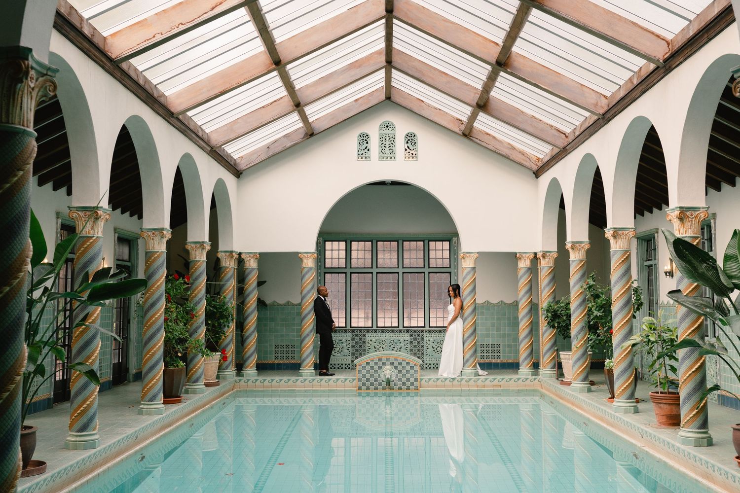 Indoor swimming pool with elegant arched colonnade and glass ceiling creating a luxurious spa atmosphere.