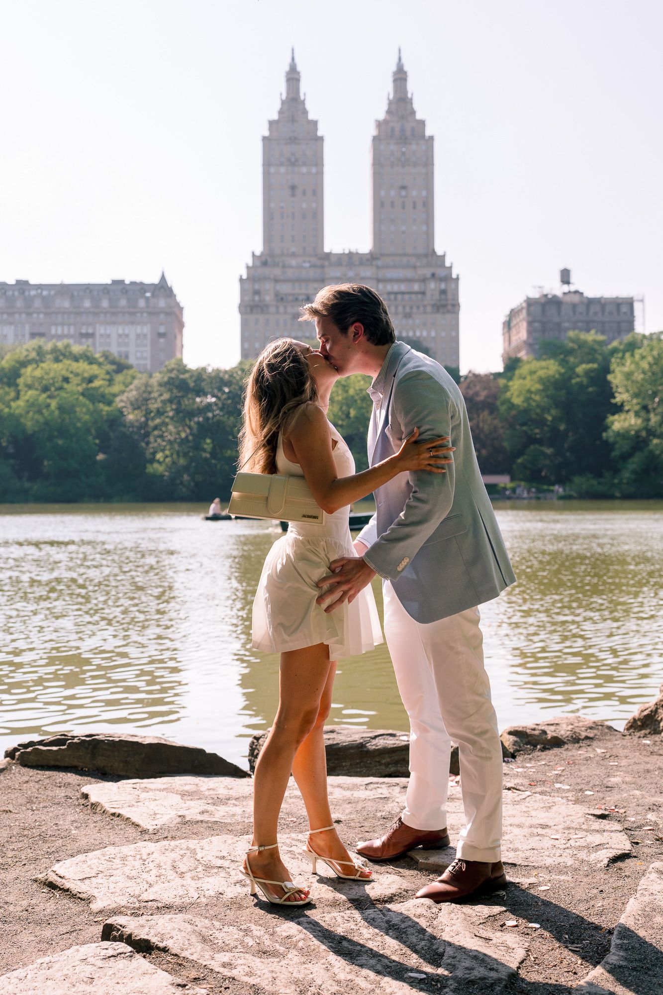 A romantic series of engagement photos by the lake in Central Park with the iconic Manhattan skyline in the background.