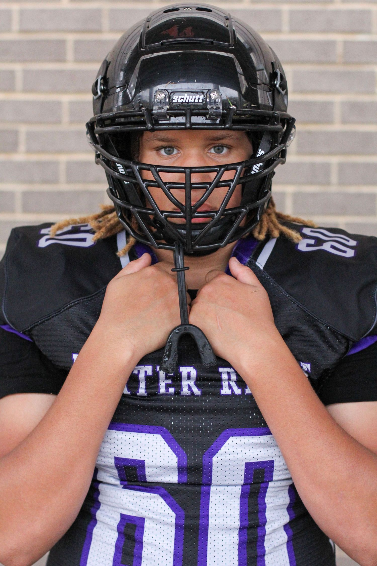 High school football player with helmet on for senior portraits at Porter Ridge.