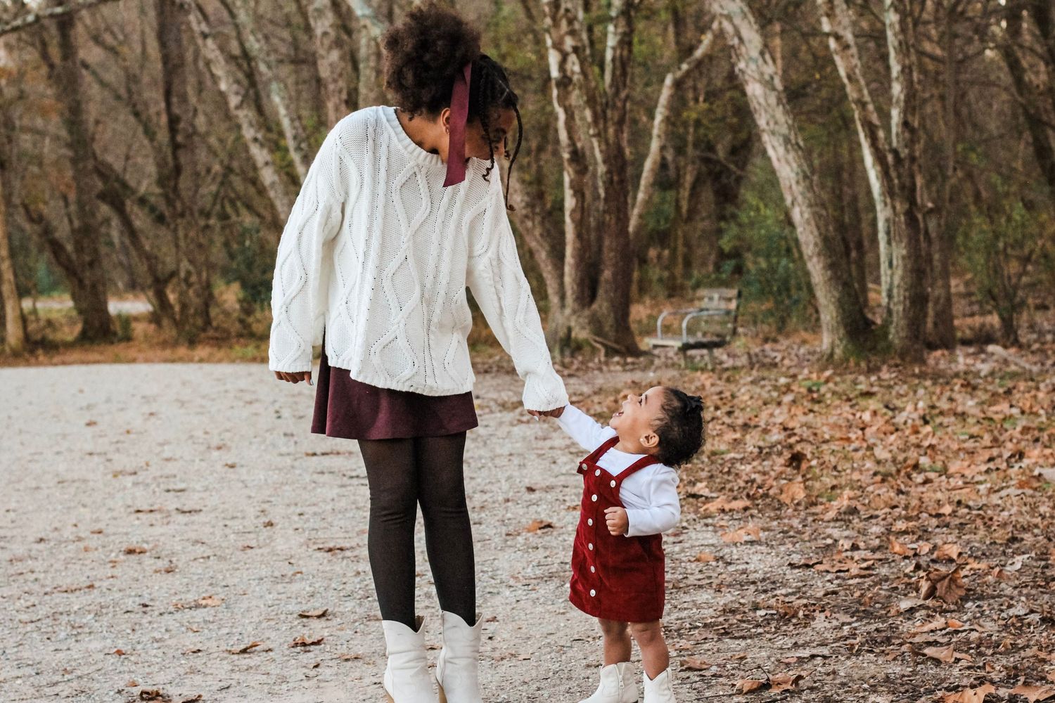 Tween and toddler holding hands, walking and laughing at McAlpine Creek Park.