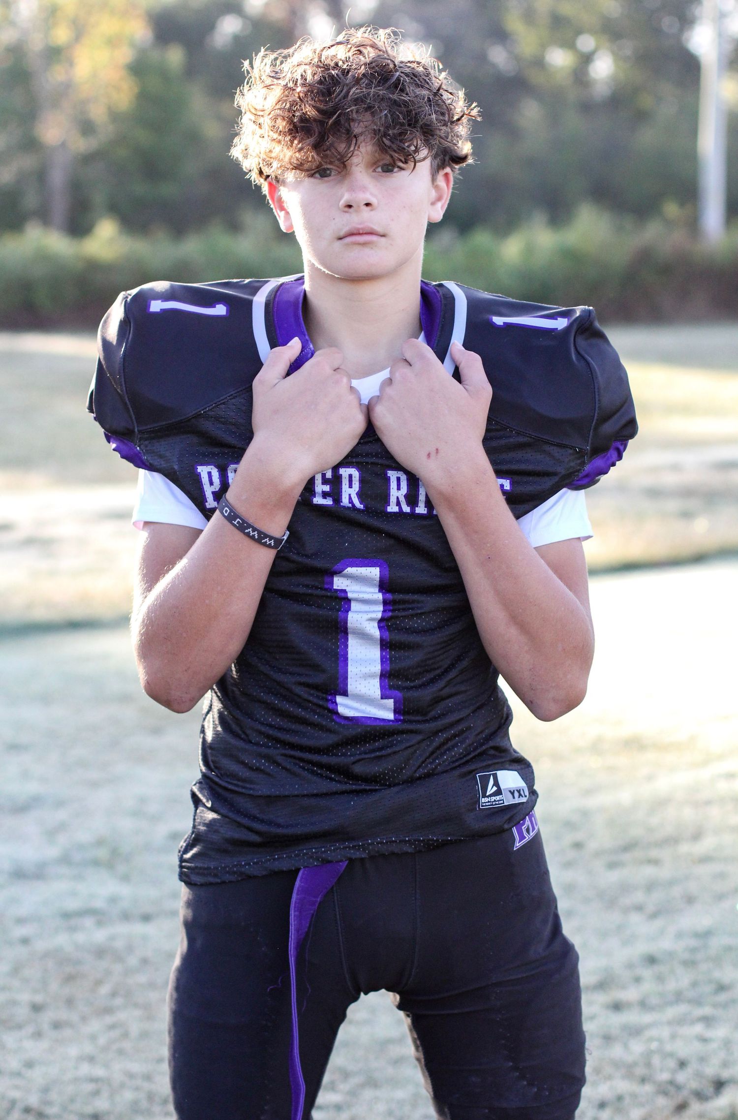 Football player posing on the field for senior sports portraits at Porter Ridge.