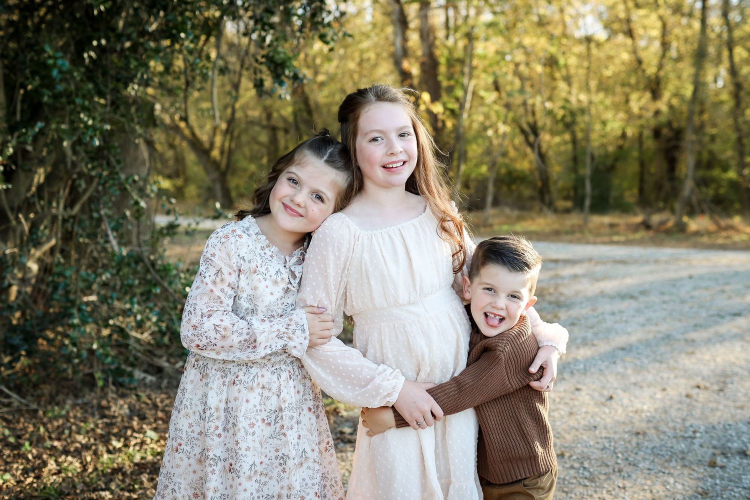 Three siblings hugging and smiling during a children's portrait session at McAlpine Park in Charlotte.