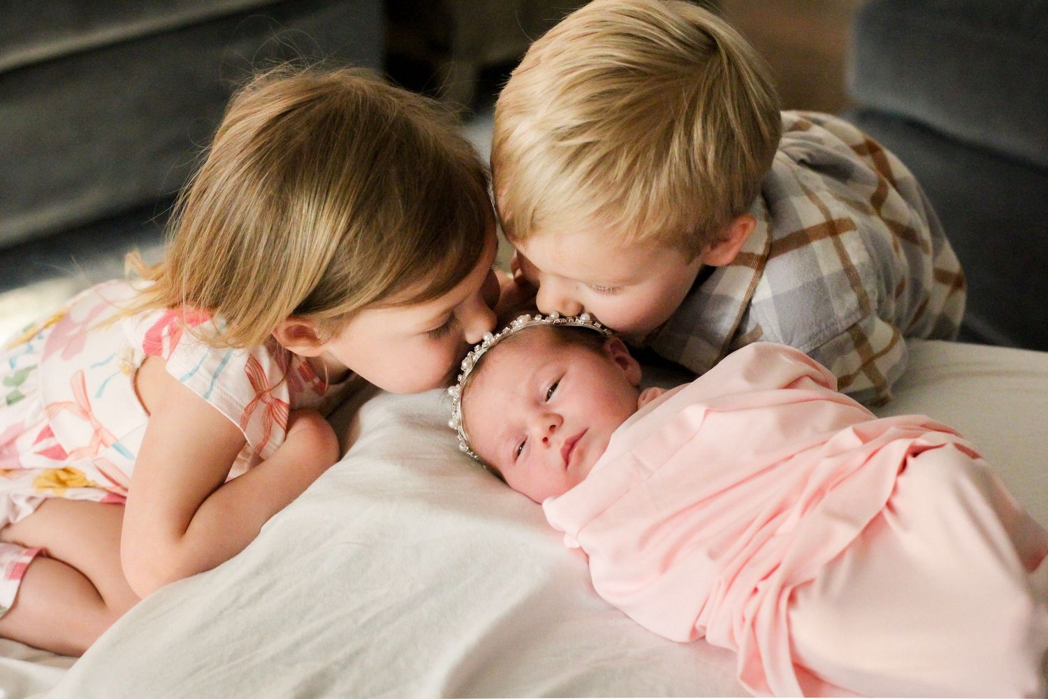 Siblings posing with their new baby sister during a Charlotte home session.