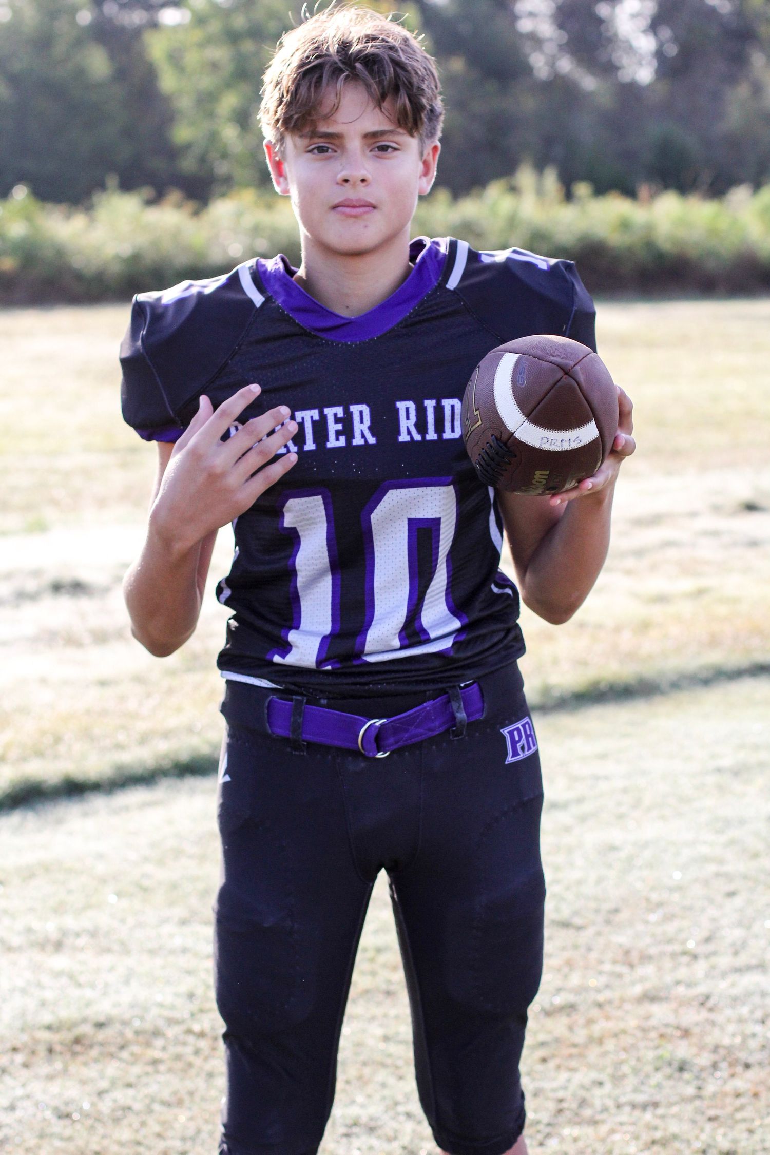 Football player posing on the field for senior sports portraits at Porter Ridge.