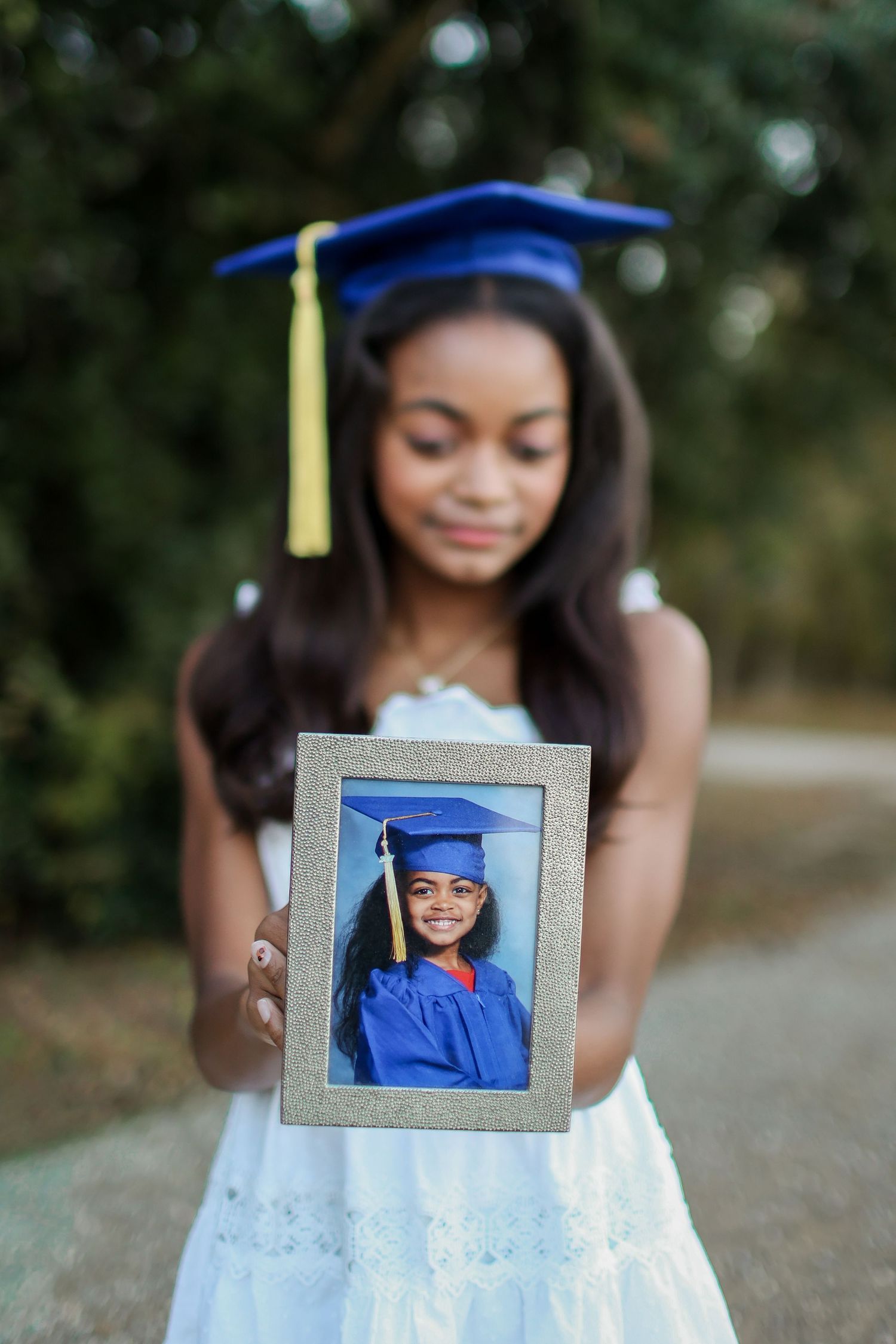 High school senior girl holding her kindergarten graduation photo for a sentimental portrait in Charlotte, NC.
