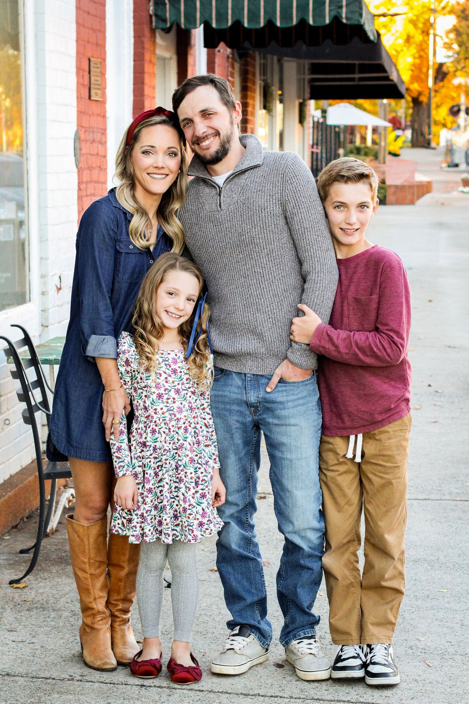 Family of four smiling for professional portraits in downtown Matthews.