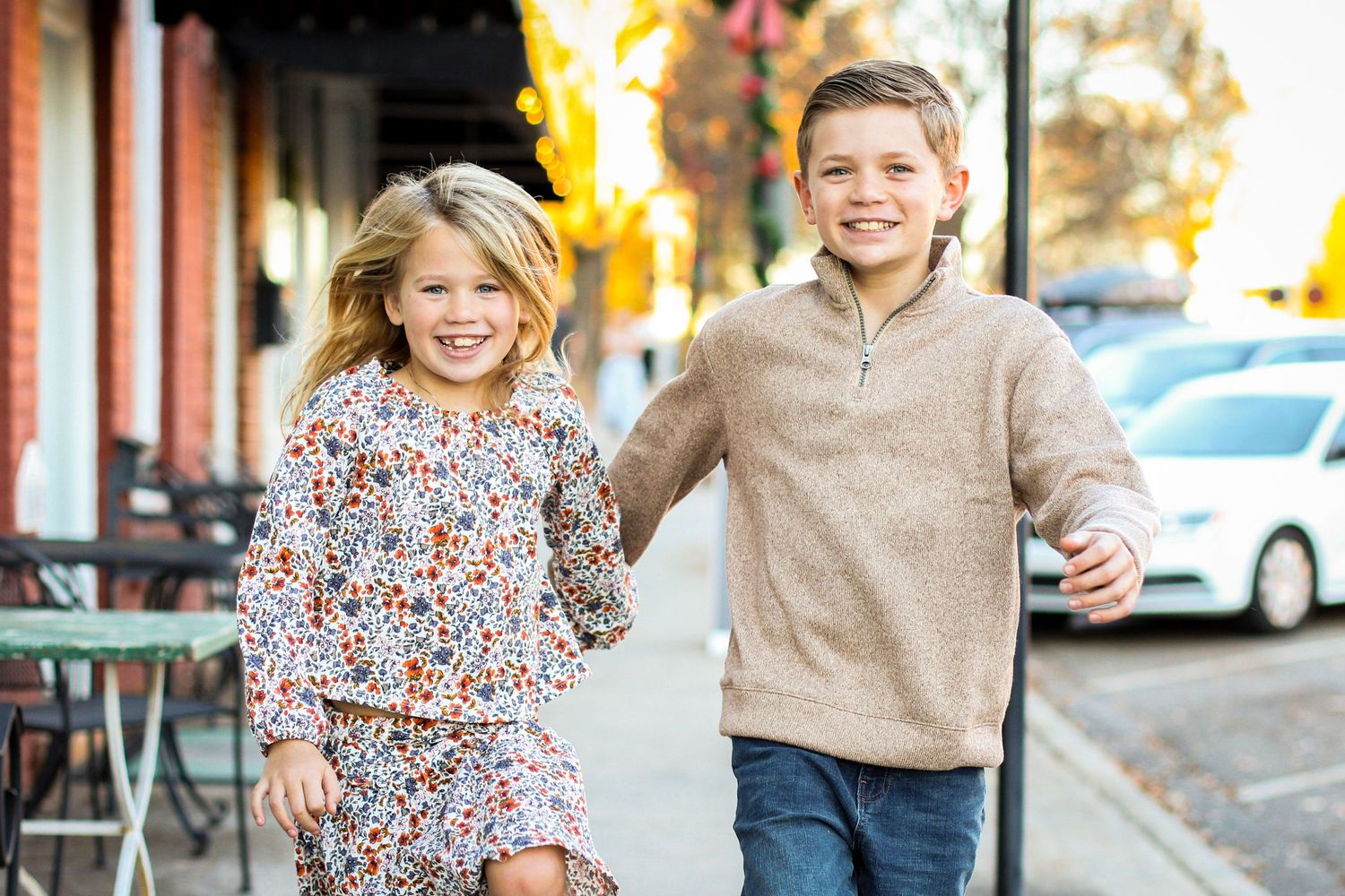 Brother and sister skipping towards the camera in downtown Matthews, NC.