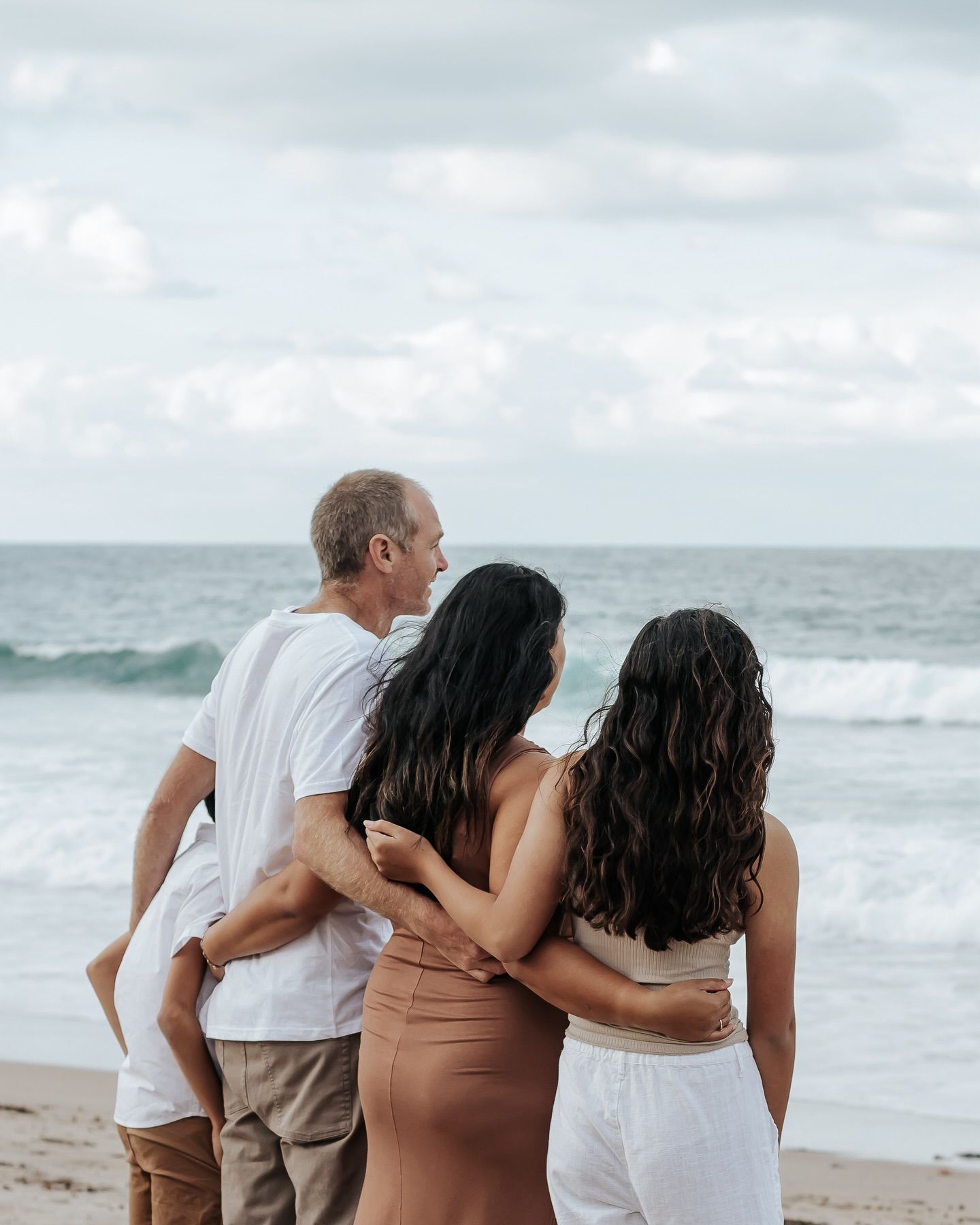 Family cuddling at Pataua north in neutral clothing
