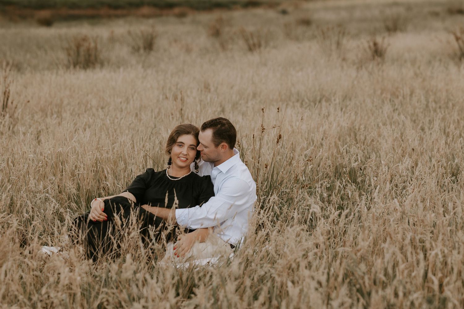 Intimate couple's portrait session in a serene field with golden grass.