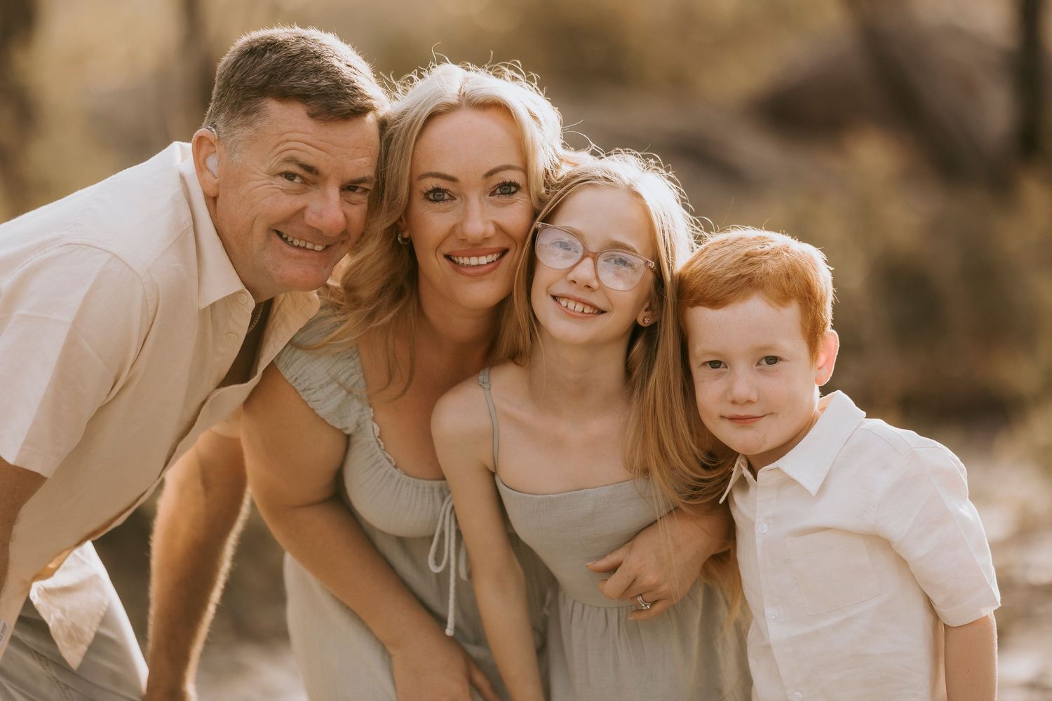 Candid family portrait showing genuine smiles and laughter in warm sunlight.