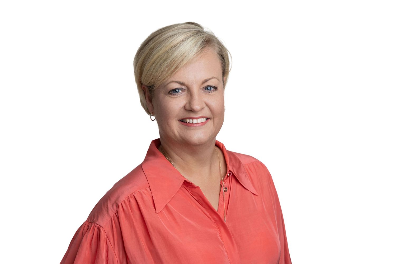 Professional headshot portrait of someone wearing a coral-colored blouse against a white background.
