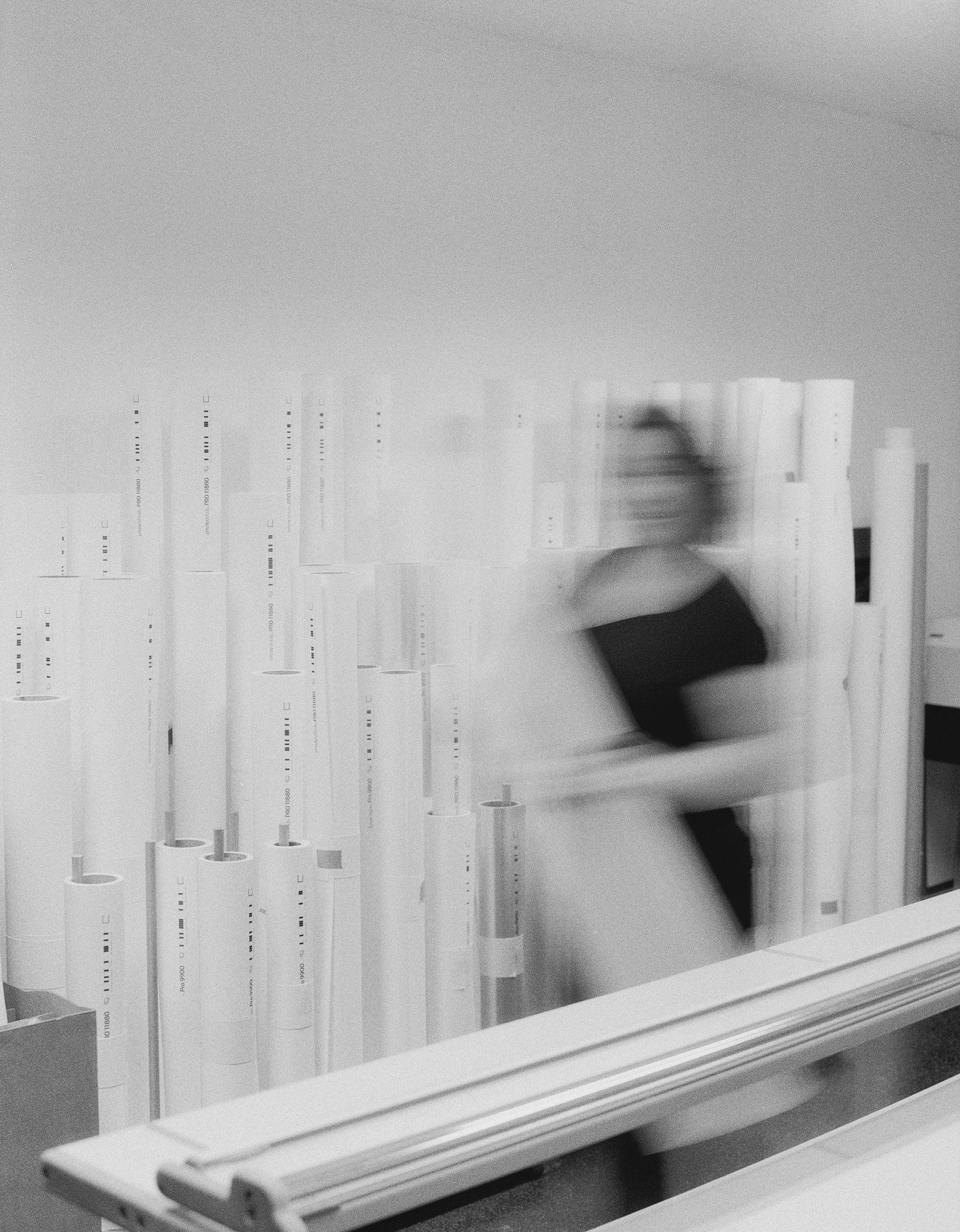 Minimalist white wall installation with blurred motion figures creating a dynamic architectural composition.