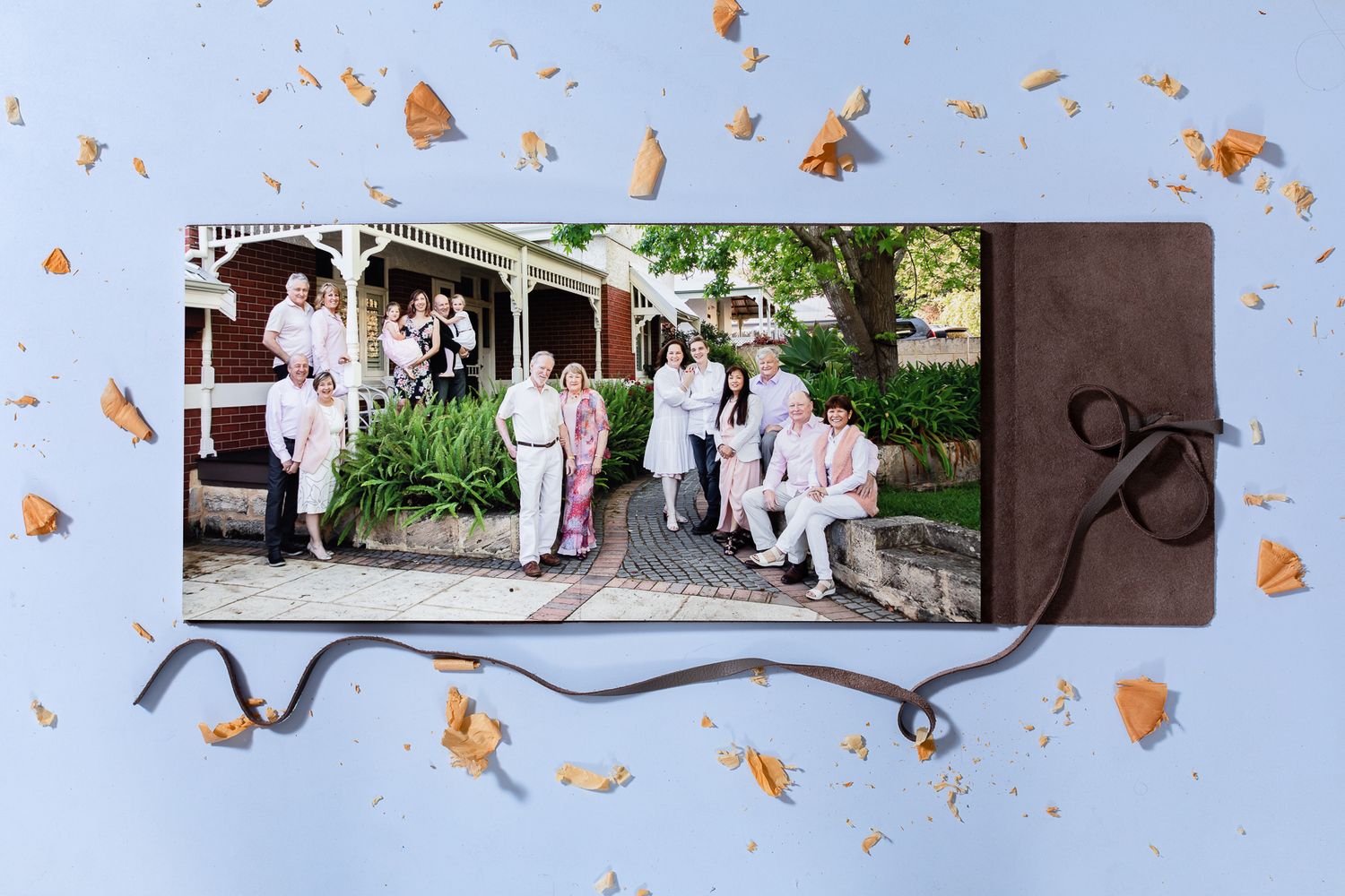 A decorative photo album page with a curved border shows a group gathering outside on a patio with fall leaves scattered around.