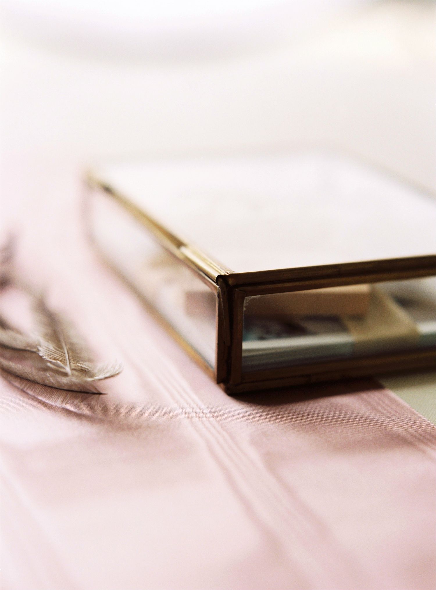A blurred silver utensil rests on a soft pink fabric surface creating an abstract minimalist composition.