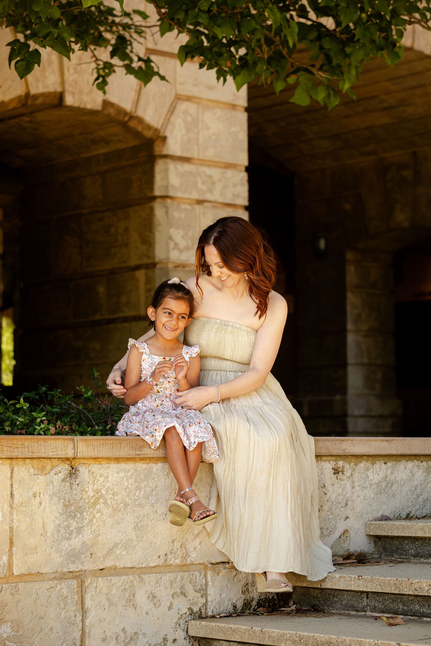 A tender moment shared between parent and child sitting on stone steps in a garden setting.