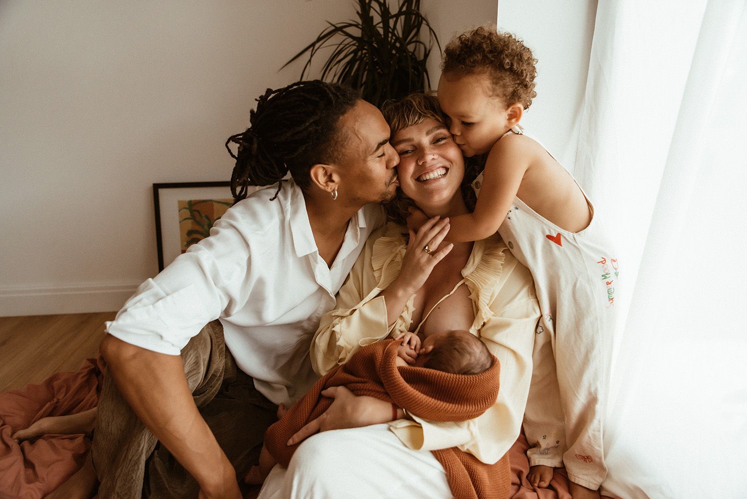 Lancashire newborn photographer. A loving family embraces while sharing a tender moment together at home in warm lighting.