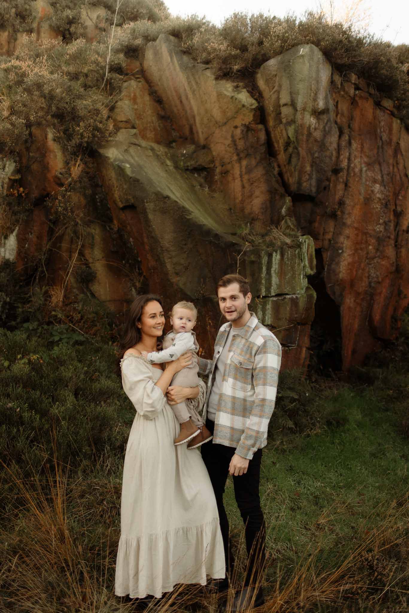 A group stands together outdoors against dramatic red rock cliffs in moody natural lighting.