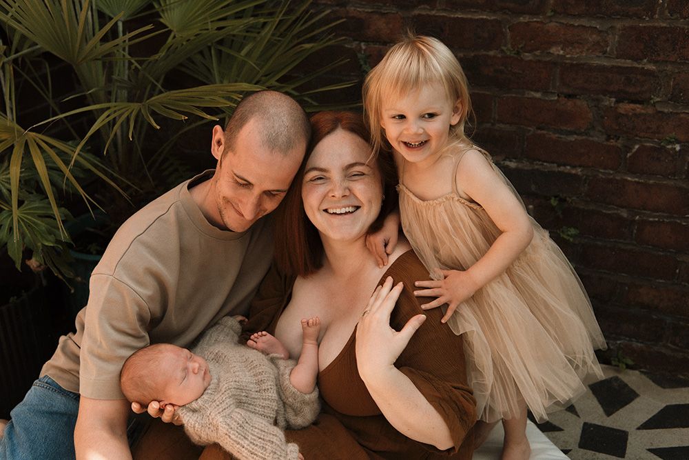 Manchester newborn and family portraits showing tender moments against a rustic brick wall background.