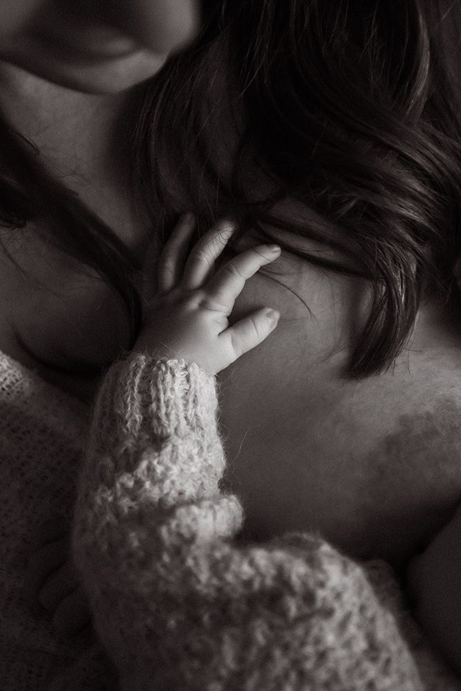 Manchester newborn photographer. A close-up black and white photo showing someone wearing a knit sweater with their hand near their face.