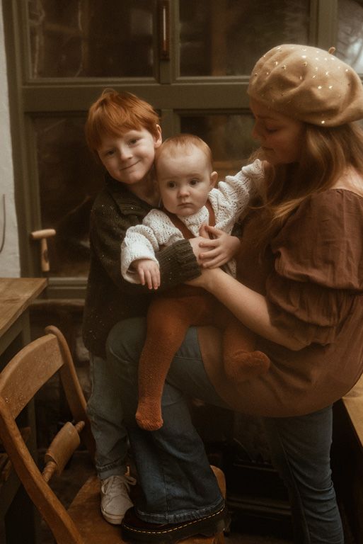 Lancashire family photographer. A vintage-style photo in warm tones showing a cosy indoor family moment with mother and her two children.