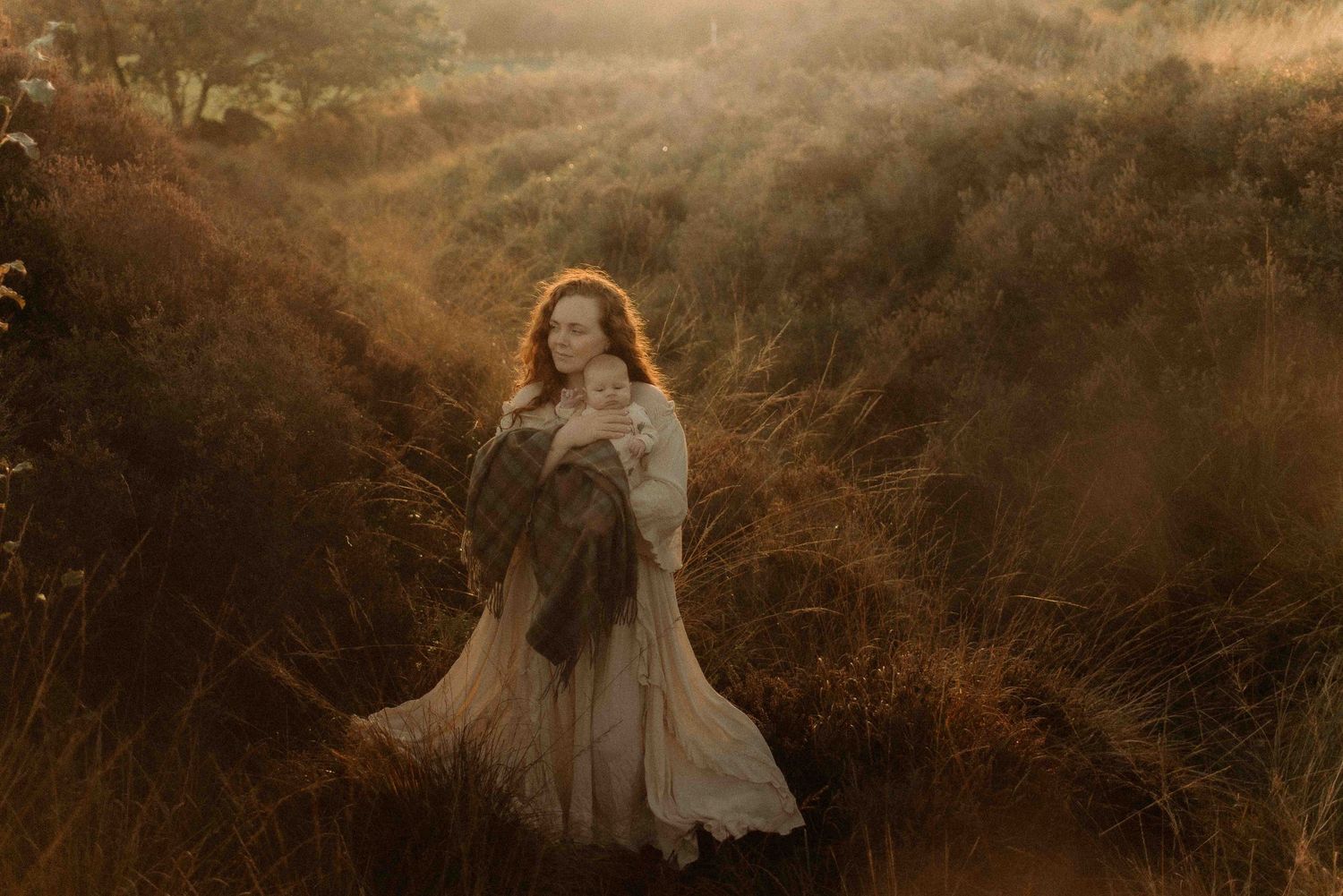 A ethereal figure in a flowing white dress stands in a golden sunlit field during magic hour.