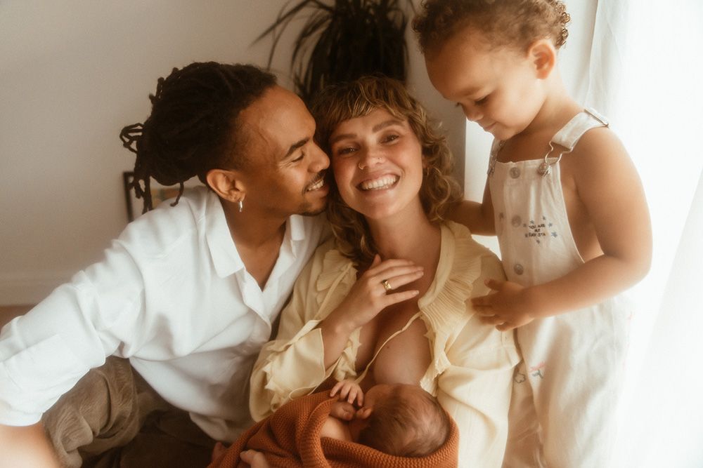 Lancashire newborn photographer. A joyful moment shared between parents & toddler in neutral tones during relaxed in home newborn session.