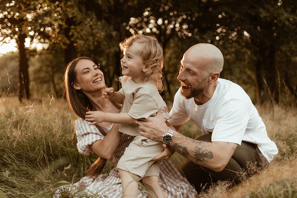 Lancashire family photographer, 3 people sitting in a sunlit field during golden hour during family photoshoot at Rivington beauty spot