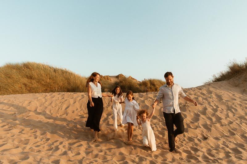 Lancashire family photographer, captures a family runs together on sandy dunes during golden hour family photoshoot at Formby beach.