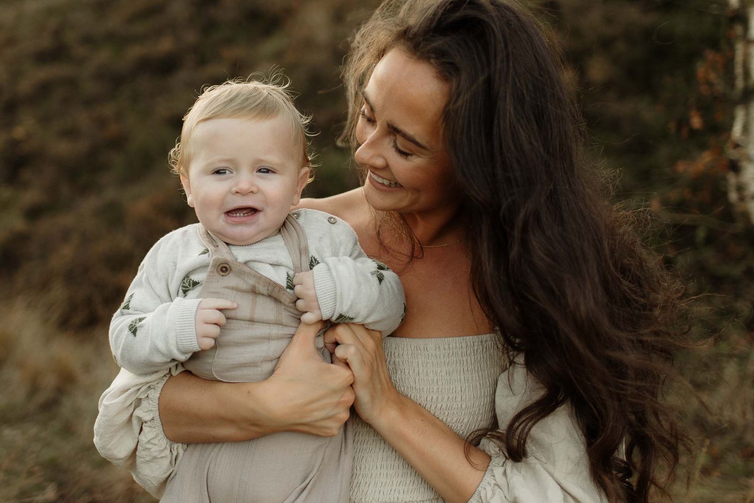 An intimate outdoor portrait of a parent and young child sharing a joyful moment together in warm natural lighting.