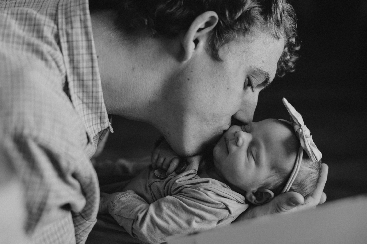 Black and white photo of dad kissing his newborn baby girl.