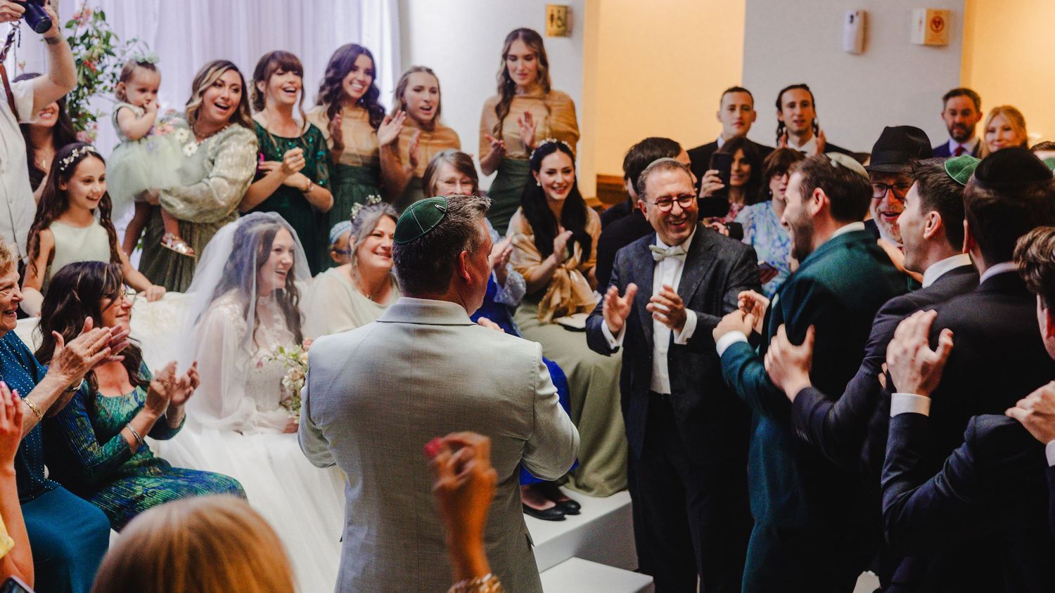 A large panoramic view of a wedding reception with guests gathered around tables in an elegant ballroom.