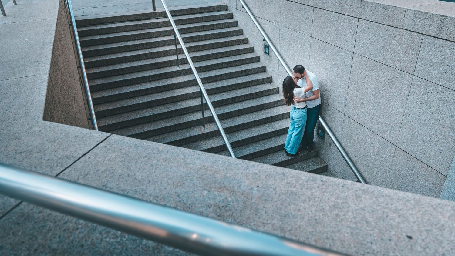 Person in a wheelchair navigates down a long concrete ramp with metal handrails on both sides.
