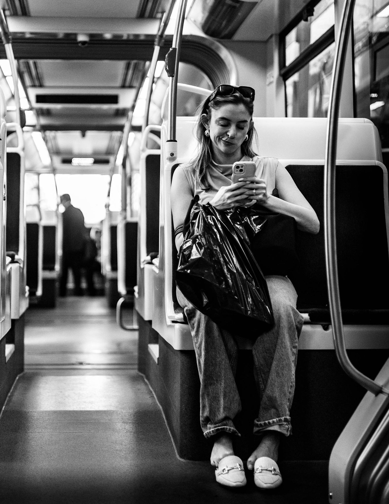 Black and white image showing passengers sitting in an empty subway train car.