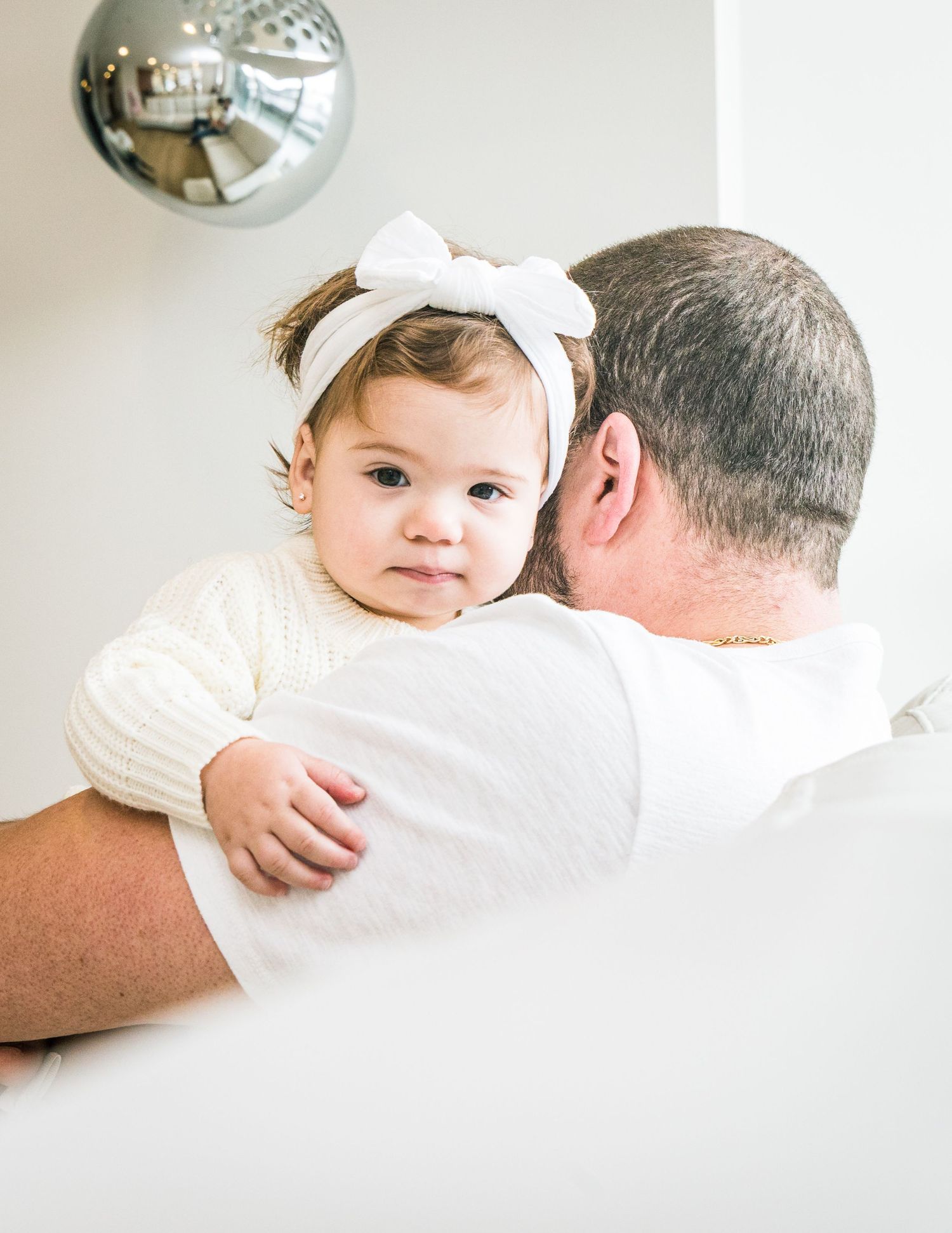 A tender black and white family portrait series showing intimate moments between parent and child against a white backdrop.