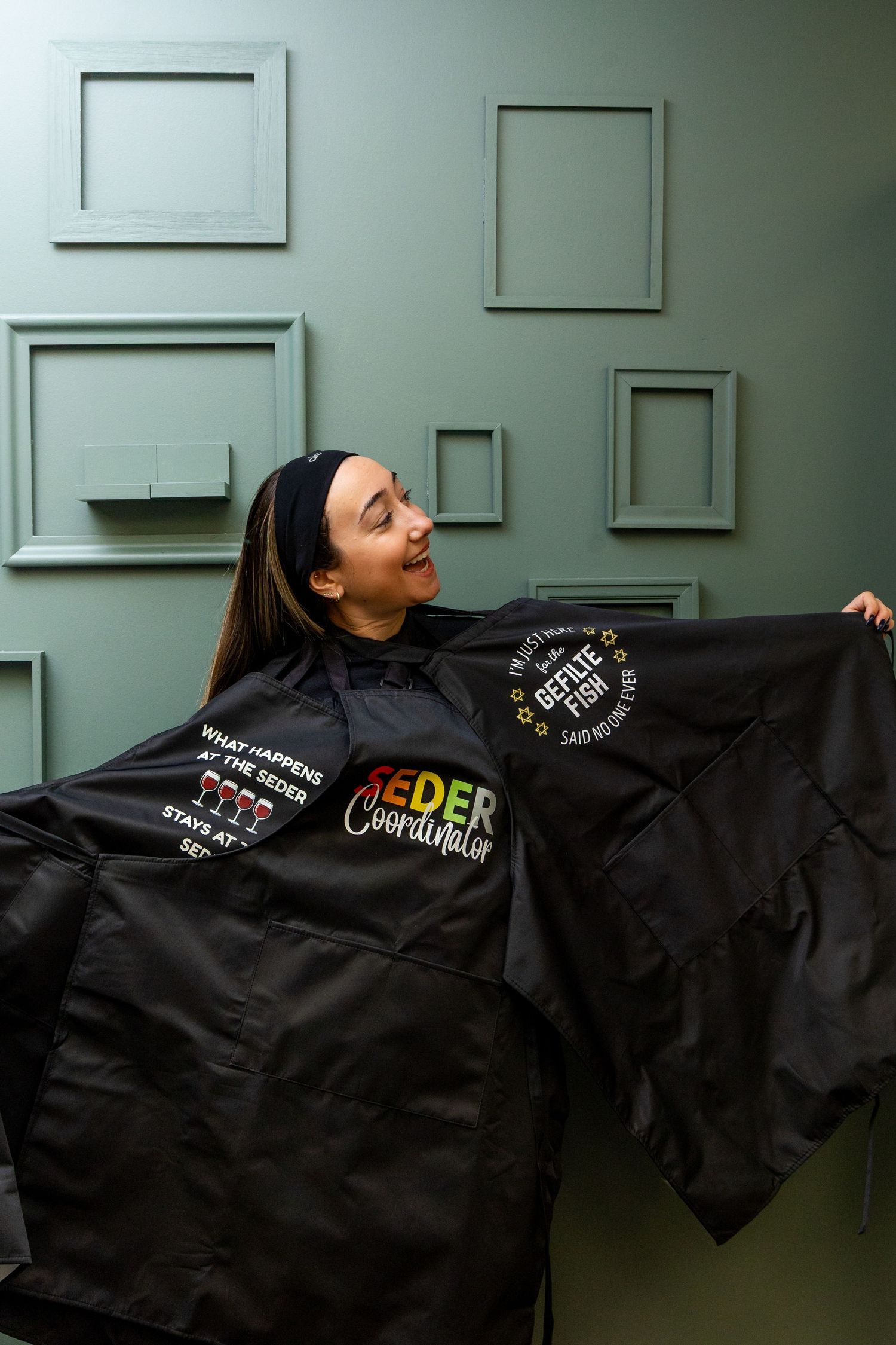 A person wearing a black jacket spreads their arms wide to display multiple embroidered patches and logos.