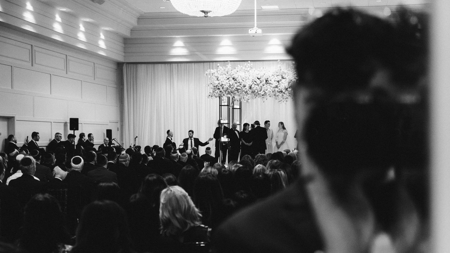 Black and white photo of an audience gathered in an indoor venue for a performance.