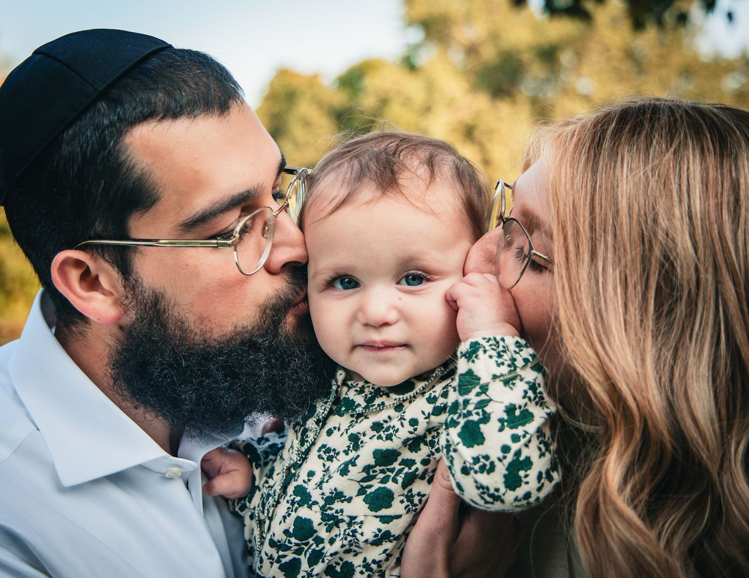 Family sharing tender moments together outdoors during a golden autumn photoshoot in a park setting.
