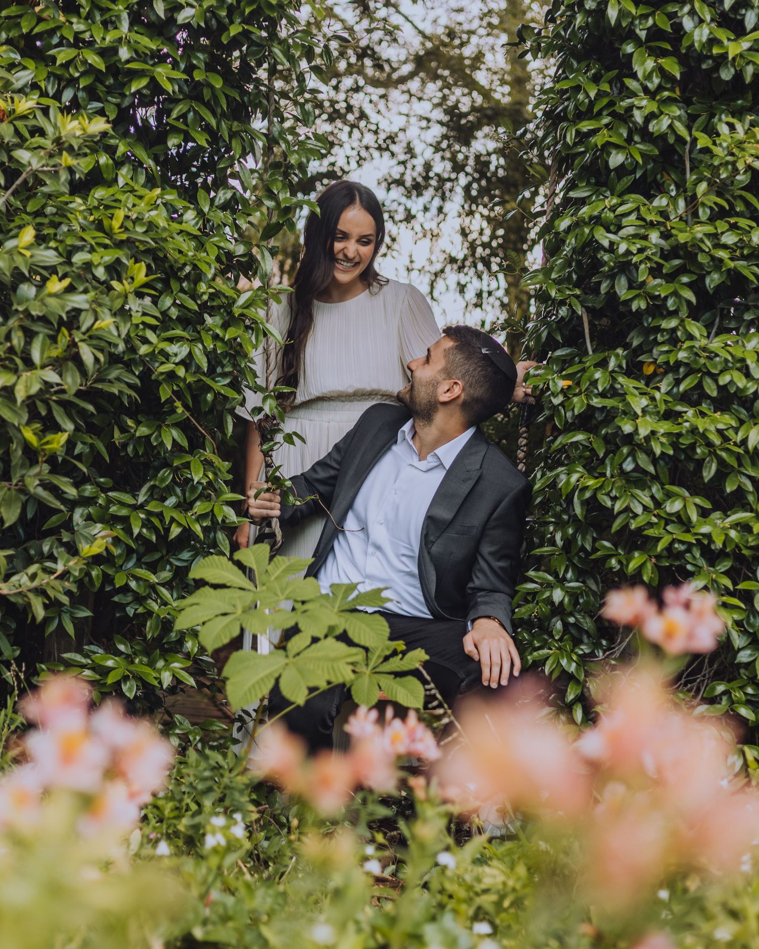 A romantic outdoor photoshoot among blooming flowers and green foliage.