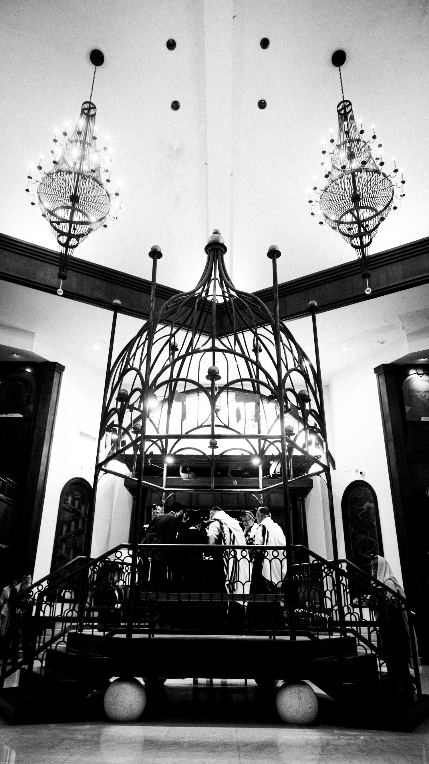 Dramatic black and white view of elaborate ceiling fixtures and architectural elements in a formal venue.