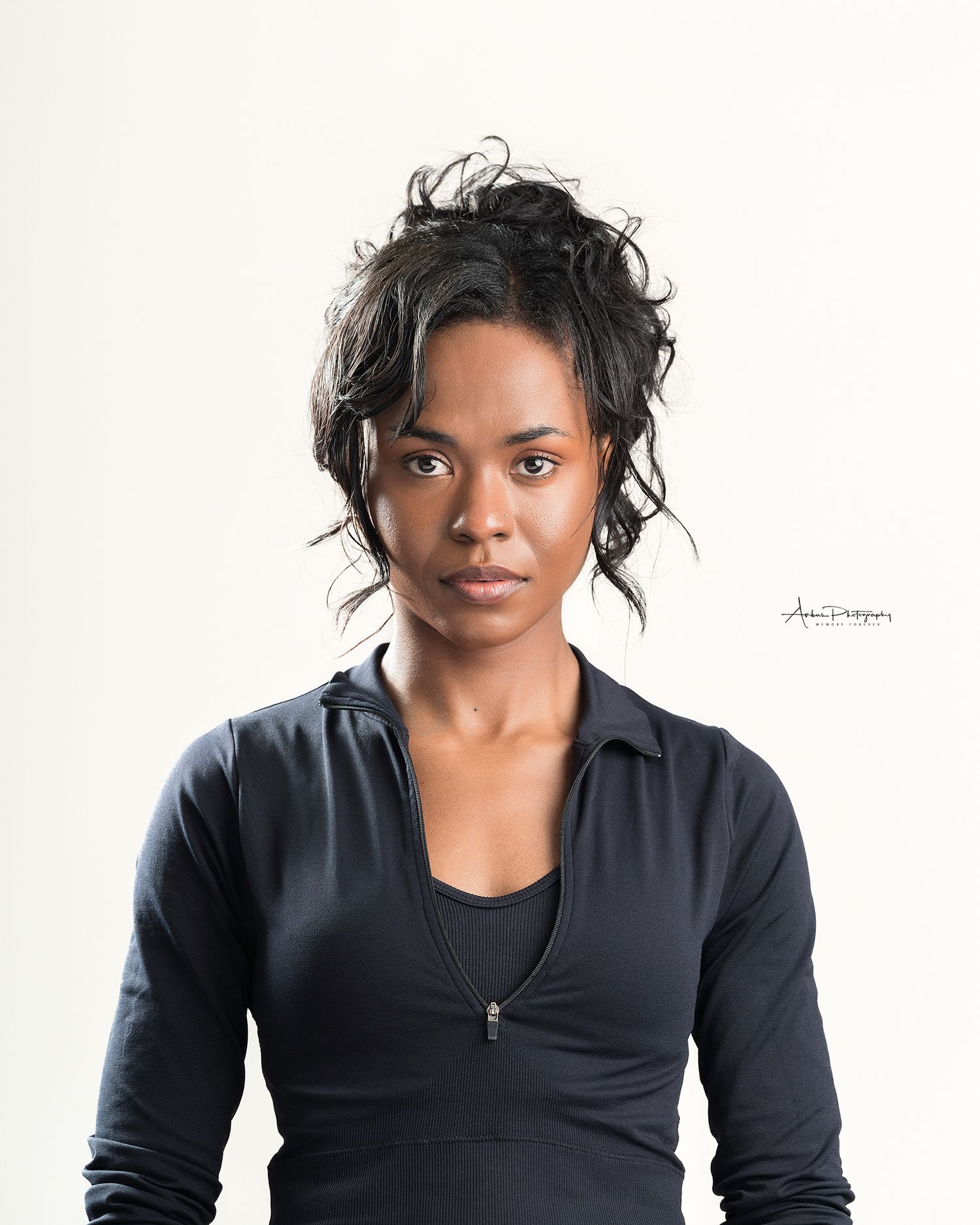 Professional studio portrait of woman in black zip-up jacket against white background.