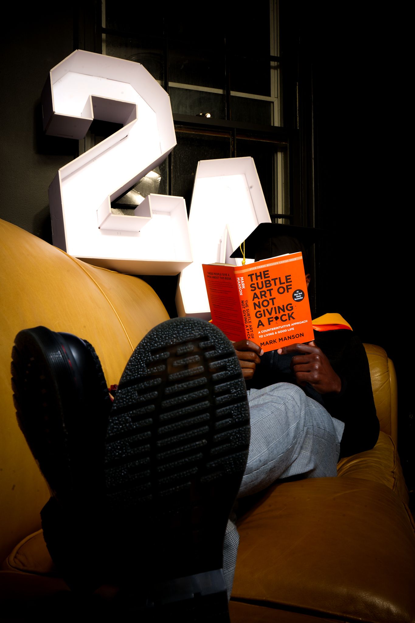 Person reading a book while lying down with illuminated numbers in dark setting.