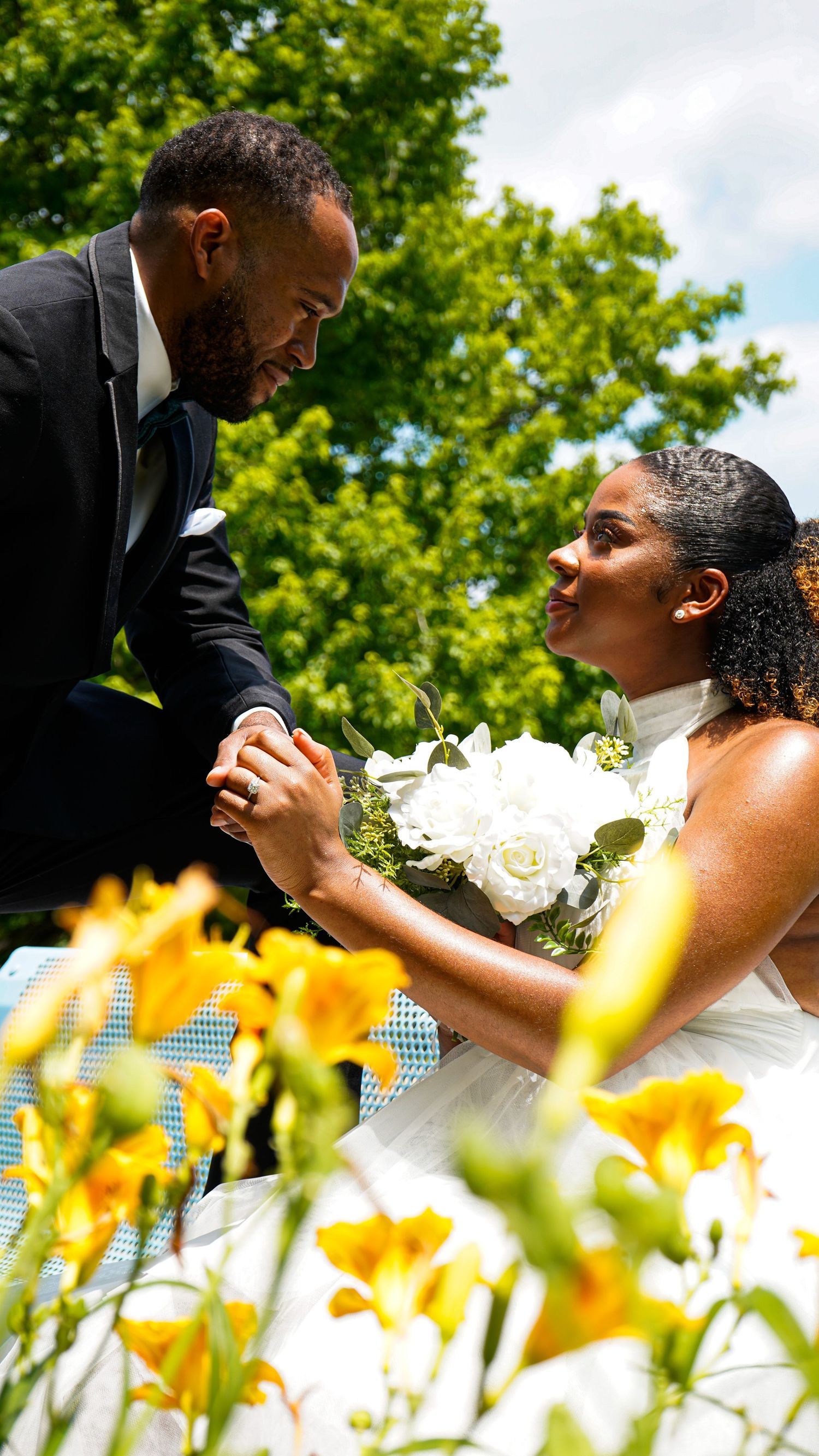 Romantic wedding couple shares tender moments among yellow flowers in a garden setting.