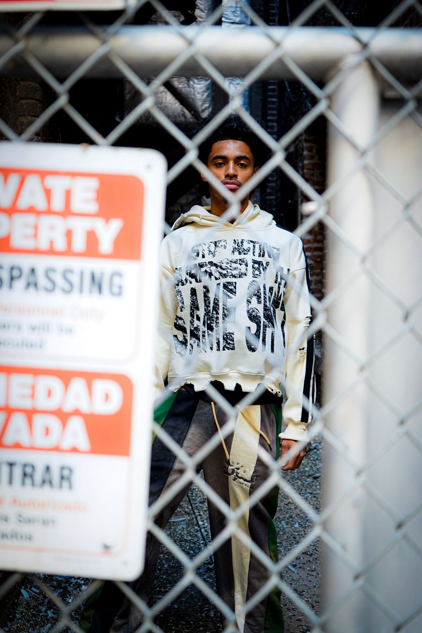 Chain-link fence with warning signs photographed in urban setting.