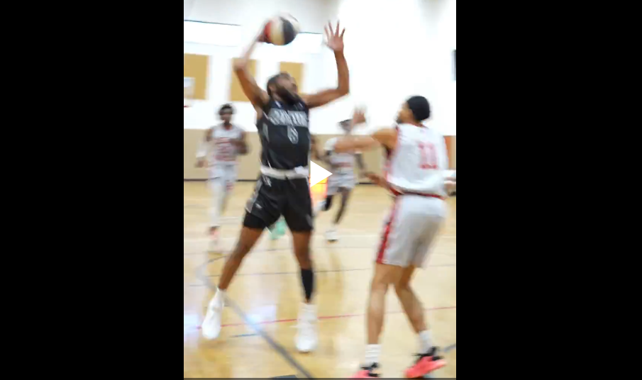 Basketball players leap high to compete for a rebound during an intense indoor game.