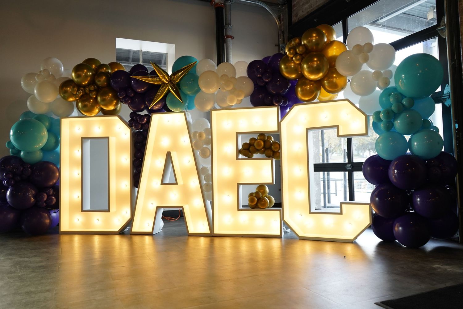 Illuminated marquee letters with balloons creating a festive party display.